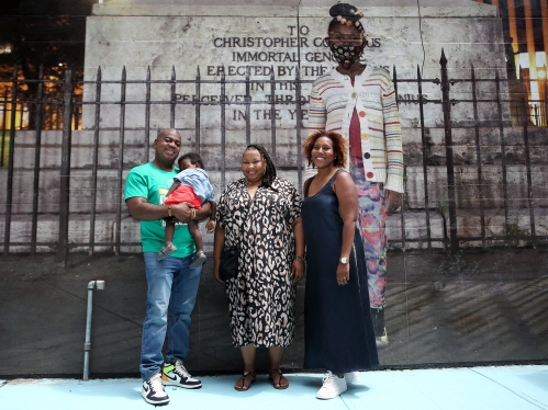 black family standing in front of photo of little black girl at a monument